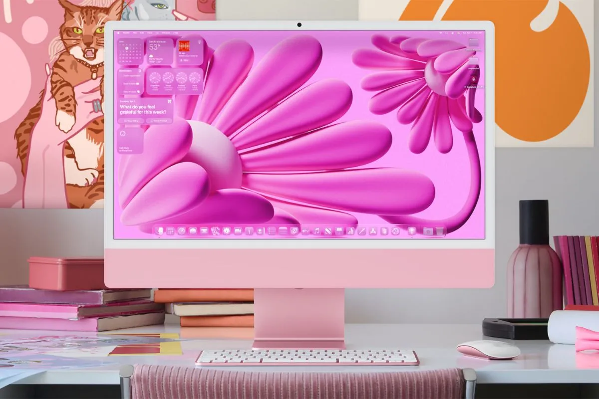 Pink Apple iMac showing macOS Tahoe 26 interface with vibrant design on screen